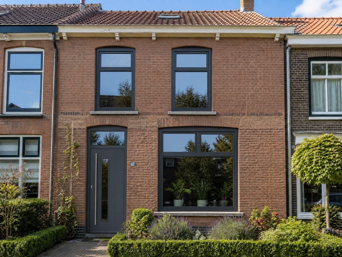 Dezelfde tussenwoning met antraciet kozijnen en moderne voordeur na montage